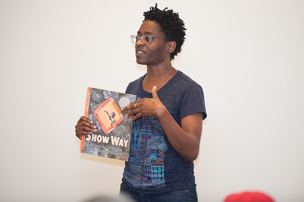 Author Jacqueline Woodson speaks, holding one of her books.