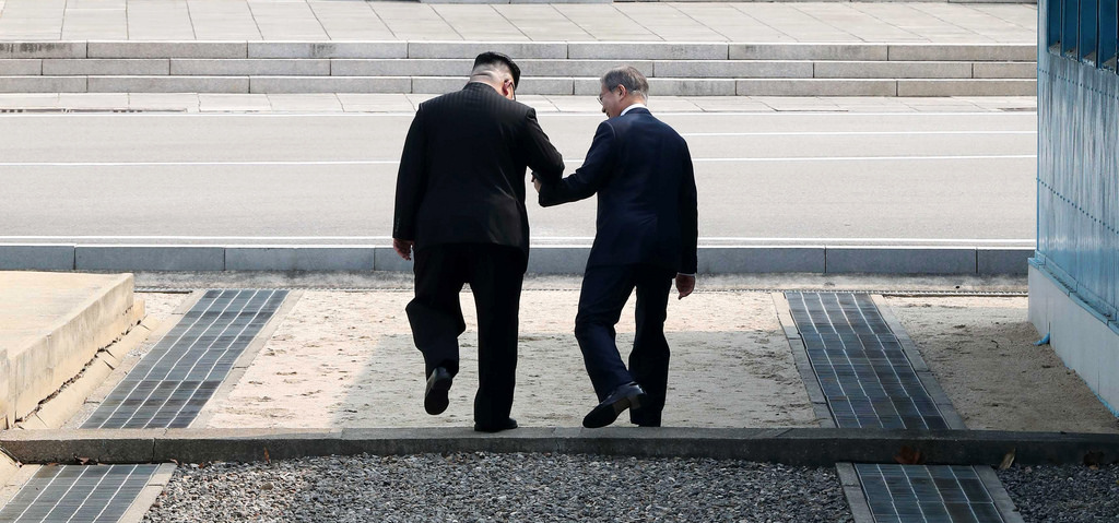 South Korean president Moon Jae-in and Kim Jong-un, the leader of North Korea, step across the border between the two countries.