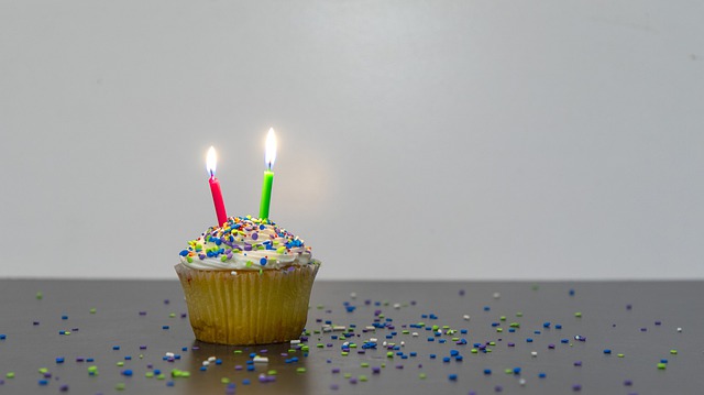 Picture of a cupcake with two lit candles on it.