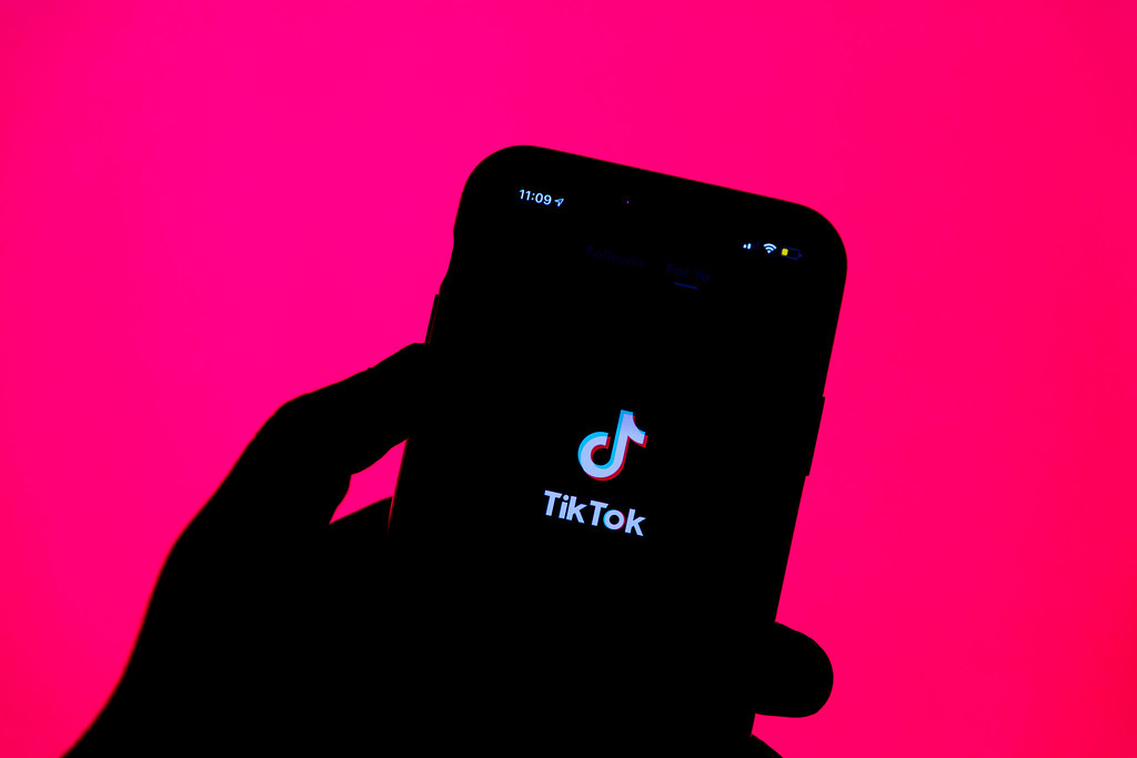 Hand holding phone showing TikTok app.