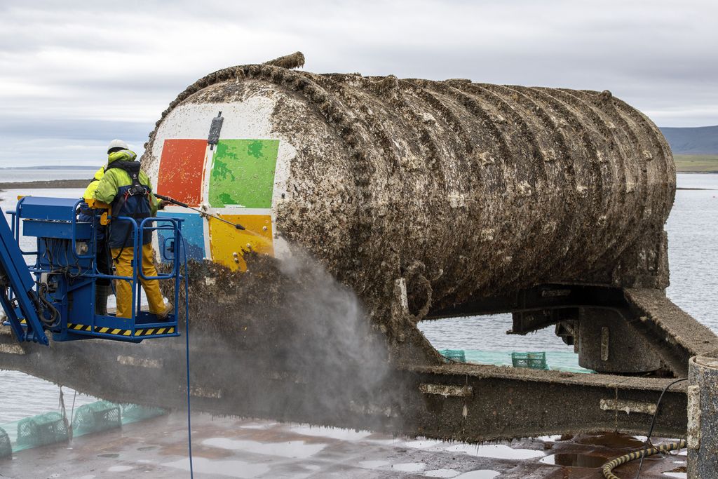 Members of the Project Natick team power wash the Northern Isles underwater datacenter, which was retrieved from the seafloor off the Orkney Islands in Scotland.