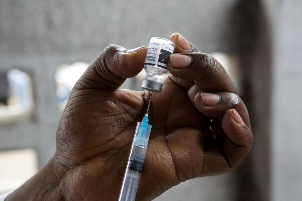 A syringe is being filled from a vaccine bottle.