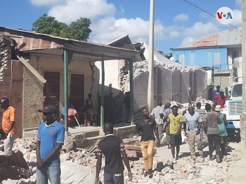 Haitians walk down the street, looking at the rubble left by the August 14 earthquake.