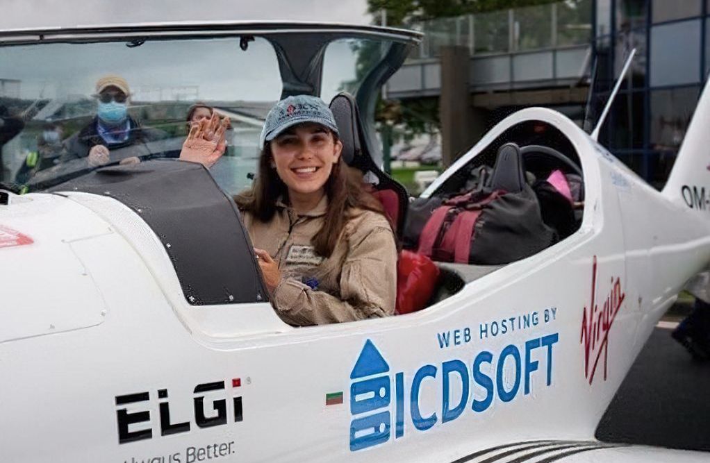 Zara Rutherford waves from the open cockpit of her plane.