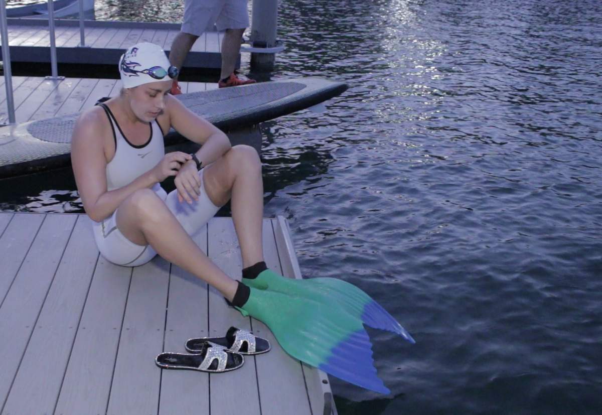 Ms. Liivand sitting on a dock wearing her monofin before setting her record.