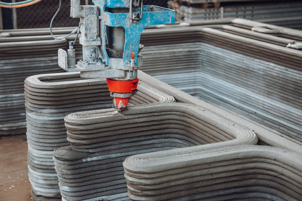 A close shot of the massive 3D-printer squirting out concrete.