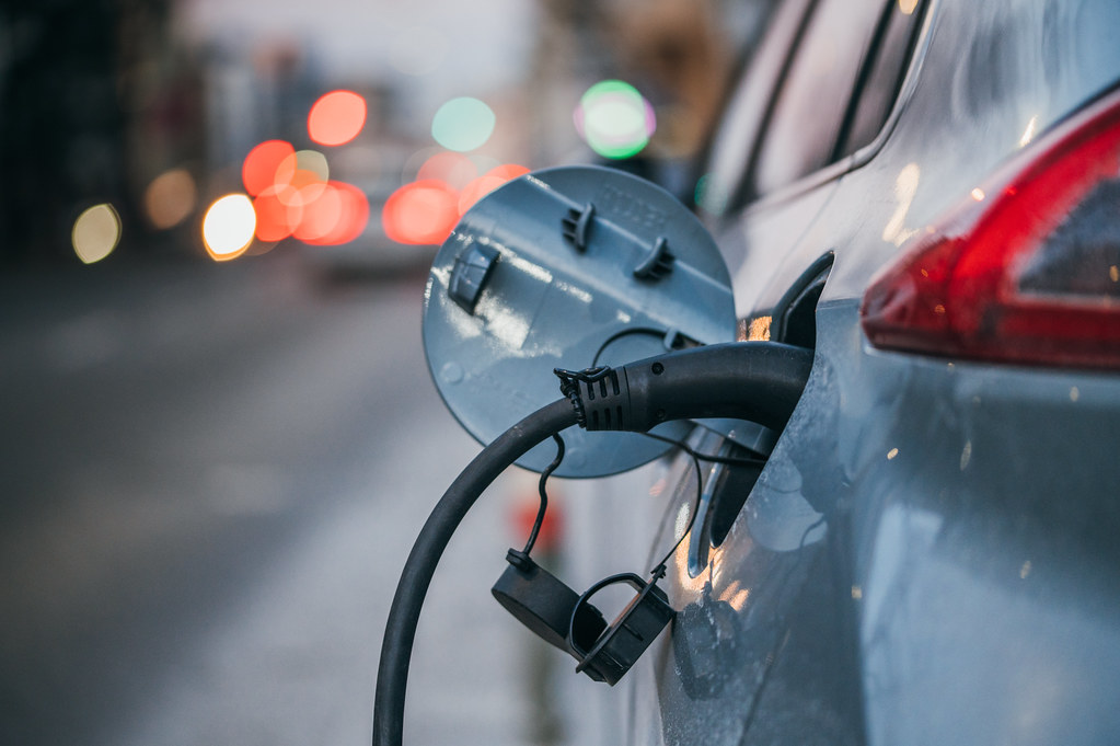 Close-up of an electric car charging. Traffic lights in a blurry background