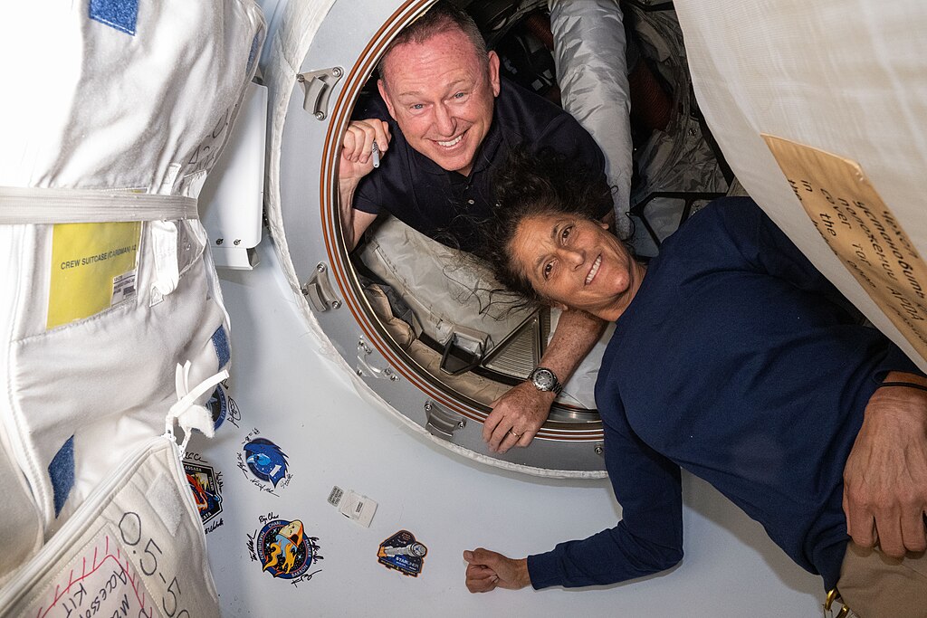 NASA's Boeing Crew Flight Test astronauts Butch Wilmore and Suni Williams pose for a portrait inside the vestibule between the forward port on the International Space Station's Harmony module and Boeing's Starliner a few days after arriving on the ISS.