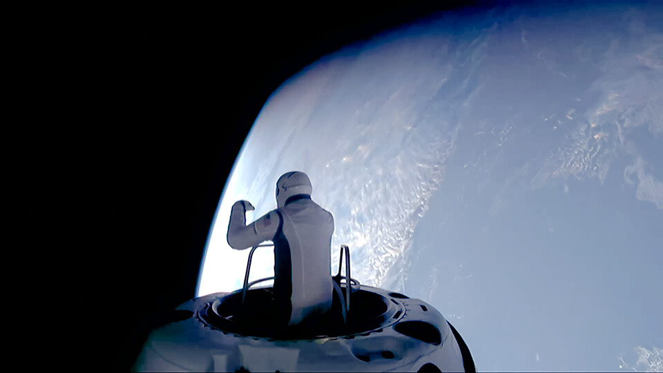 Jared Isaacman seen with his torso above the Crew Dragon capsule and the Earth in the background during first commercial spacewalk.